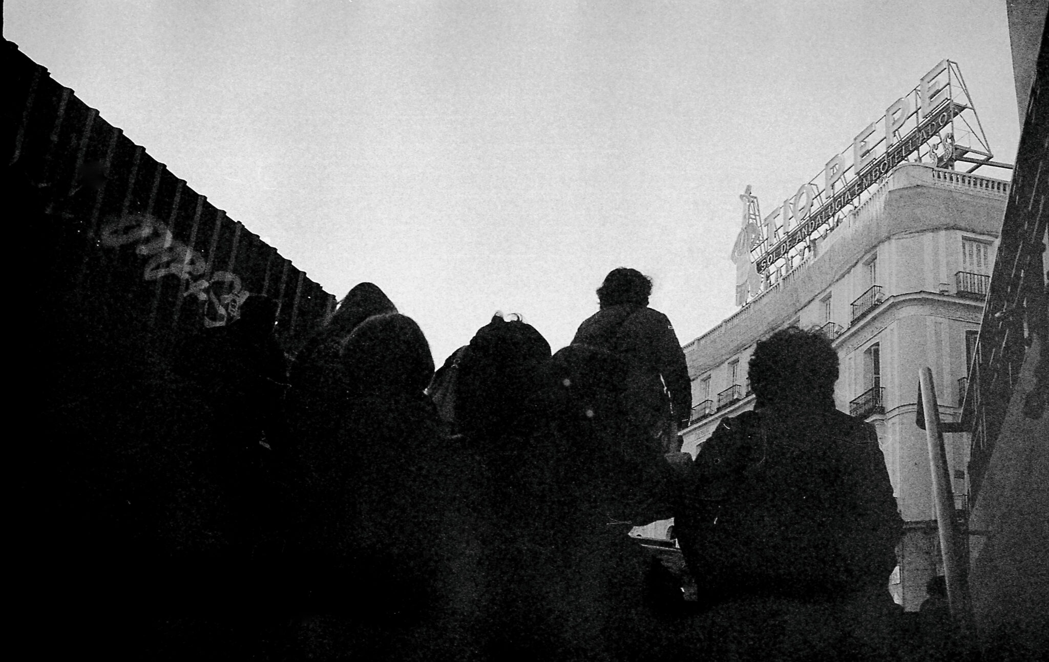 Black and white picture of people leaving the Sol metro station in Madrid with the Tío Pepe sign in the background